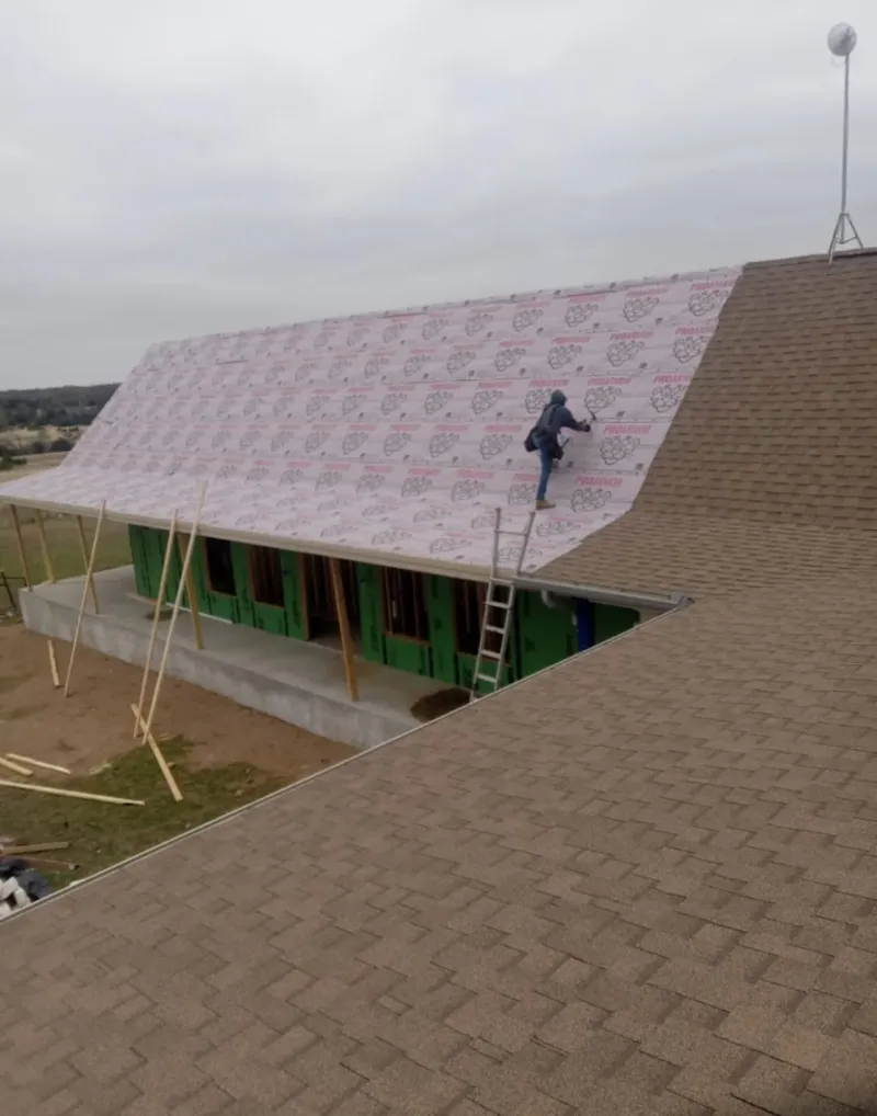 Worker preparing underlayment for a metal roof installation in Sterling
